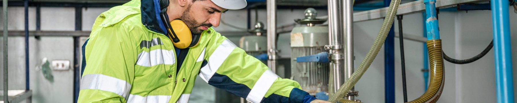 Caucasian technician engineer man in uniform with tablet checking and control boiler tanks and liquid pipeline in chemical factory production line