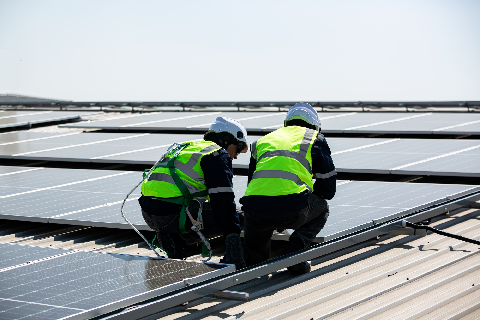 Solar panel installer installing solar panels on roof of warehouse